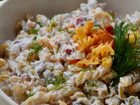 Cremiger Nudelsalat mit frischem Dill in einer weißen Schüssel