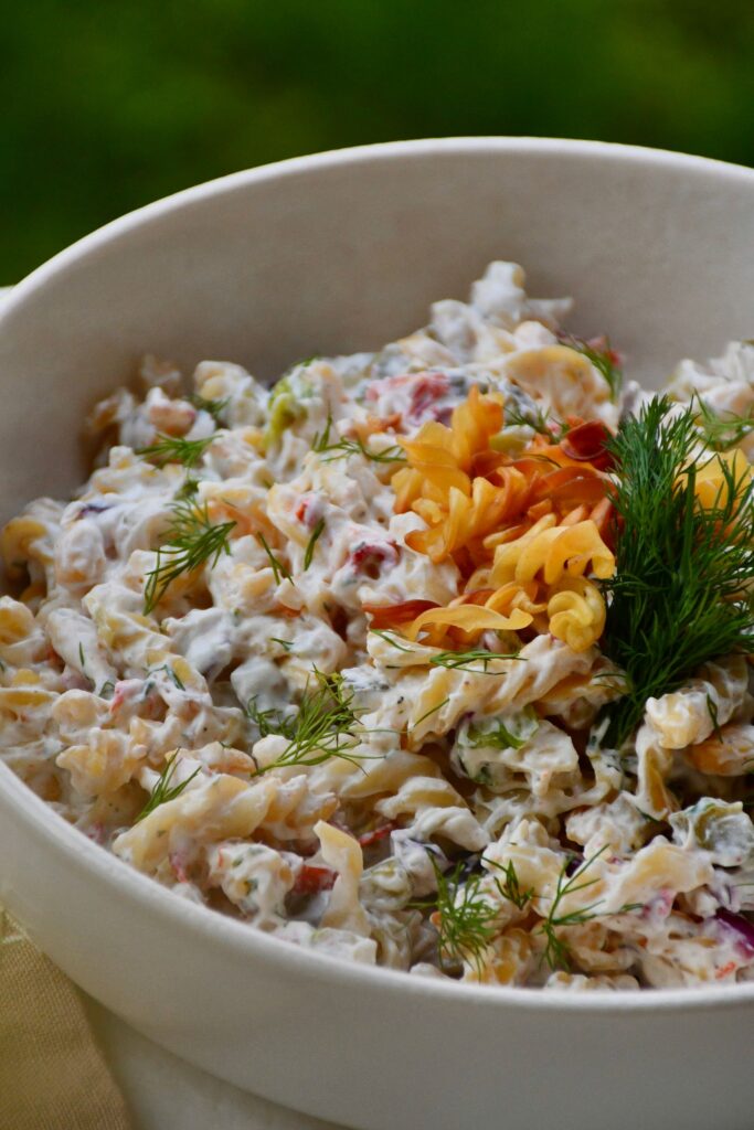 Cremiger Nudelsalat mit frischem Dill in einer weißen Schüssel